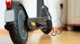 An,E-scooter,Is,Charged,At,Home,Using,A,Power,Cable.